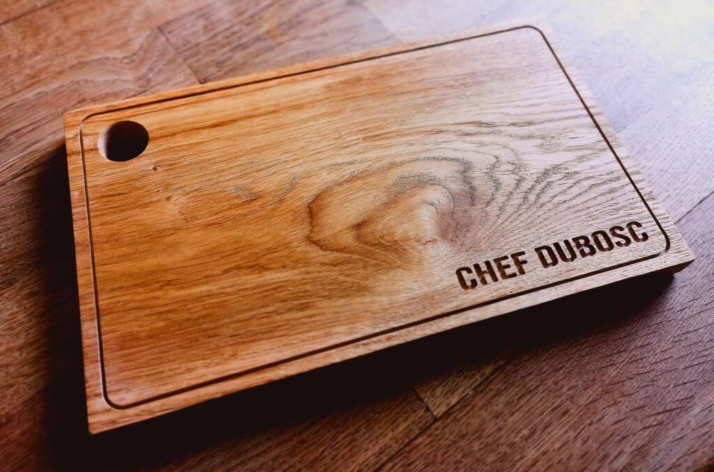 Planche à découper en bois de chêne massif personnalisée avec le texte 'CHEF DUBOSC', fabriquée par Manufacture Dubosc et Fils. Idéale pour les amateurs de cuisine et les chefs, cette planche artisanale est un accessoire de cuisine durable et esthétique, disponible sur notre boutique en ligne.