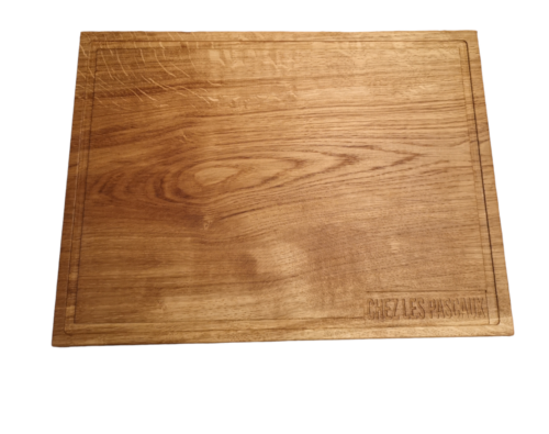 Planche en bois massif personnalisée avec inscription 'Chez les Pascaux', fabriquée par Manufacture Dubosc et Fils. Planche à découper en chêne durable, idéale pour servir fromages et charcuteries, conçue avec des matériaux naturels et écoresponsables. Disponible sur notre boutique en ligne.