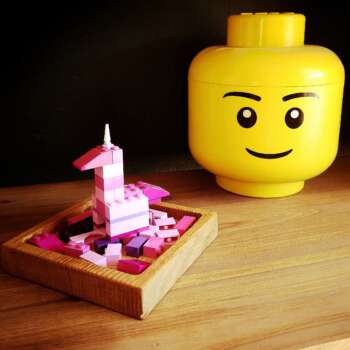 Vide-poche carré en chêne massif avec en fond une tete de lego et un lego rose en construction
