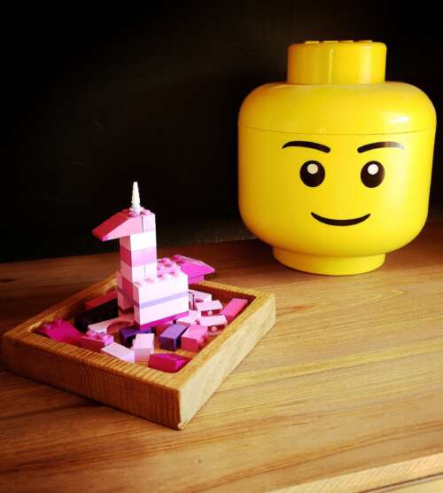 Vide-poche carré en chêne massif avec en fond une tete de lego et un lego rose en construction