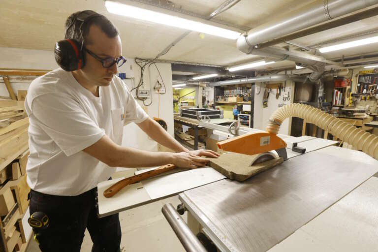 Sami Dubosc Artisan de Manufacture Dubosc et Fils utilisant une scie à format pour découper une planche en bois massif, dans notre atelier spécialisé à Deluz. Chez Manufacture Dubosc et Fils, nous concevons des meubles et accessoires en bois personnalisés, tout en mettant l'accent sur la qualité, la durabilité et le respect des matières premières. Découvrez notre gamme complète de produits artisanaux disponibles sur notre boutique en ligne.