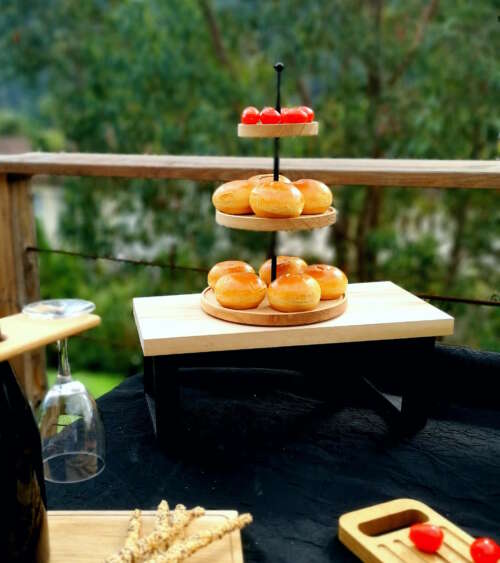 Présentoir à 3 niveaux en bois massif garni de pains et fruits lors d’un buffet élégant en extérieur.