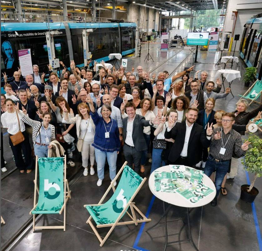 Photo de groupe des partenaires lors de l'événement 'Boosteur de Bonheur' à Besançon, avec un tramway en arrière-plan et des participants célébrant l'initiative. Manufacture Dubosc et Fils est fière de soutenir des événements qui valorisent l'artisanat local , la durabilité, et le savoir-faire traditionnel. Cet engagement reflète nos valeurs d'éco-responsabilité et de qualité artisanale. La qualité des accessoires en bois durable proposée par Manufacture Dubosc et Fils ajoute une touche artisanale et écologique à cet évènement.