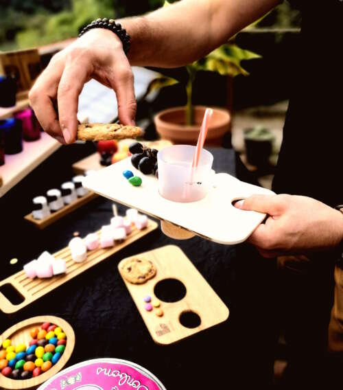 Planche apéritif en bois éco-responsable, faite main, avec un design fonctionnel permettant de tenir un verre à pied et des snacks. Accessoire en bois durable, fabriqué artisanalement à partir de matériaux recyclés, incarnant le savoir-faire local et une approche zéro déchet. Idéal pour des événements, avec une éthique de fabrication et un design sur-mesure