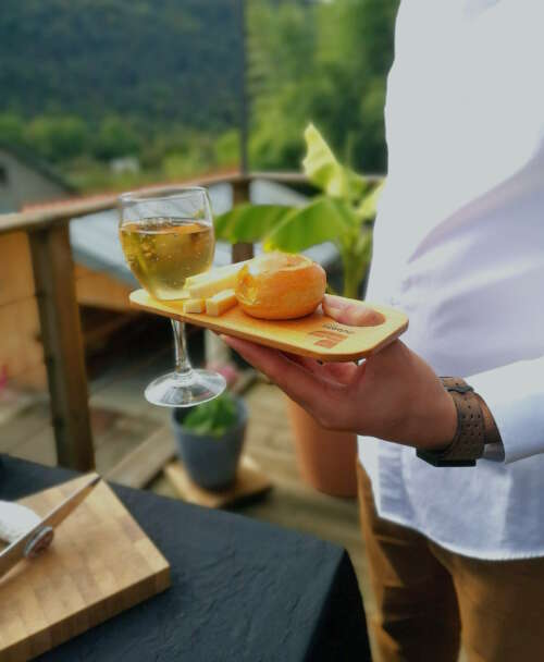 Planche apéritif en bois éco-responsable, faite main, avec un design fonctionnel permettant de tenir un verre à pied et des snacks et du Comté. Accessoire en bois durable, fabriqué artisanalement à partir de matériaux recyclés, incarnant le savoir-faire local et une approche zéro déchet. Idéal pour des événements, avec une éthique de fabrication et un design sur-mesure.