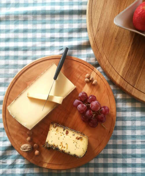 Plateau tournant en bois massif de 35 cm de Manufacture Dubosc et Fils, avec un assortiment de fromage, raisins, noisettes, et noix. Ce plateau artisanal est idéal pour des présentations de table conviviales et élégantes, permettant de servir facilement fromages et charcuteries avec style.