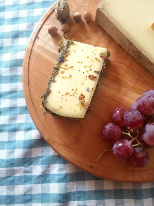 Plateau tournant en bois massif de 35 cm de Manufacture Dubosc et Fils, présentant un fromage affiné aux herbes, des raisins, des noisettes et une noix. Ce plateau élégant et naturel est idéal pour des présentations de fromages et charcuteries, parfait pour des repas conviviaux et gourmands.