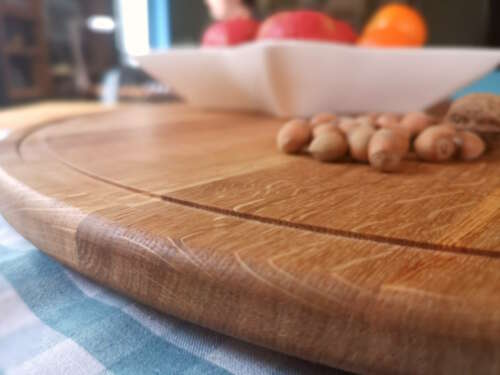 Vue rapprochée d'un plateau tournant en chêne massif de Manufacture Dubosc et Fils, avec des noisettes et des fruits en arrière-plan. Ce plateau élégant et naturel est conçu pour des présentations conviviales, ajoutant une touche chaleureuse à la table.