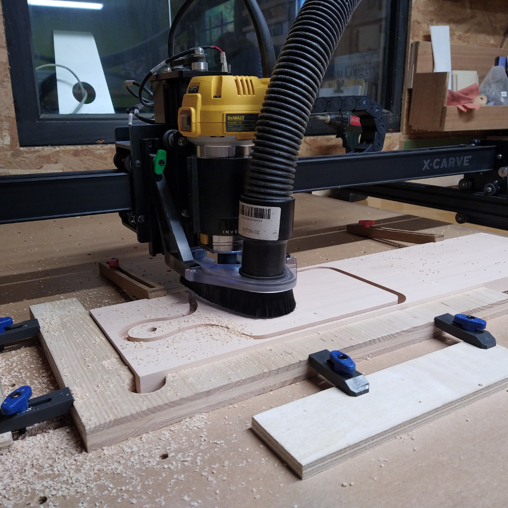 Image d'une machine CNC en plein travail de découpe d'une planche à découper en bois massif local dans l'atelier de la Manufacture Dubosc et Fils. Ce processus de fabrication artisanal et précis illustre le savoir-faire unique de notre entreprise, dédiée à la création d'objets en bois sur mesure et personnalisés. Ces planches, conçues en collaboration avec la scierie Moyne, mettent en valeur le bois local et la qualité artisanale de notre région.