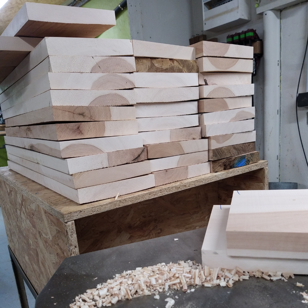 Planche de bois massif en cours de rabotage dans l’atelier artisanal de Manufacture Dubosc et Fils. Ce processus de finition, réalisé avec précision, illustre le soin apporté à la transformation du bois local brut en créations uniques. Nos artisans qualifiés transforment ces matières premières en objets personnalisés tels que des planches apéritives, des doseurs ou encore des présentoirs en bois massif. Explorez notre boutique en ligne pour découvrir nos produits écoresponsables alliant durabilité et design intemporel.