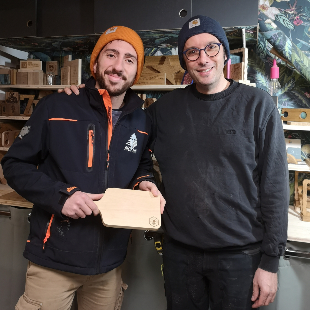 Pierre Moyne de la scierie Moyne et Sami Dubosc de Manufacture Dubosc et Fils posent fièrement avec une planche à découper en bois massif, conçue comme récompense pour le challenge Moyne Doubs Terre de Trail. Cette collaboration met en valeur le bois local et le savoir-faire artisanal, alliant durabilité et design personnalisé. L'atelier Manufacture Dubosc et Fils transforme le bois brut en objets uniques et écoresponsables, disponibles sur leur boutique en ligne. Découvrez leurs créations : planches apéritifs, accessoires personnalisés, et bien plus.