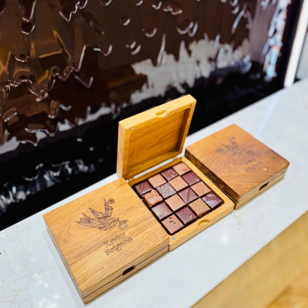 Coffret en bois massif gravé, conçu par Manufacture Dubosc et Fils, renfermant des chocolats d'exception du maître artisan chocolatier Xavier Brignon. Ce produit artisanal met en avant le savoir-faire local et l'élégance du design personnalisé. Avec son mécanisme astucieux et son allure raffinée, ce coffret est parfait pour offrir ou sublimer vos dégustations. Fabriqué à partir de bois noble et gravé sur mesure, il constitue un cadeau unique alliant tradition et modernité. Découvrez nos créations artisanales et personnalisées sur notre boutique en ligne.