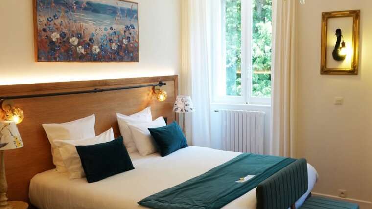 Chambre d’hôtel raffinée avec mobilier sur mesure en bois massif, réalisée par la Manufacture Dubosc et Fils au Château de la Dame Blanche.