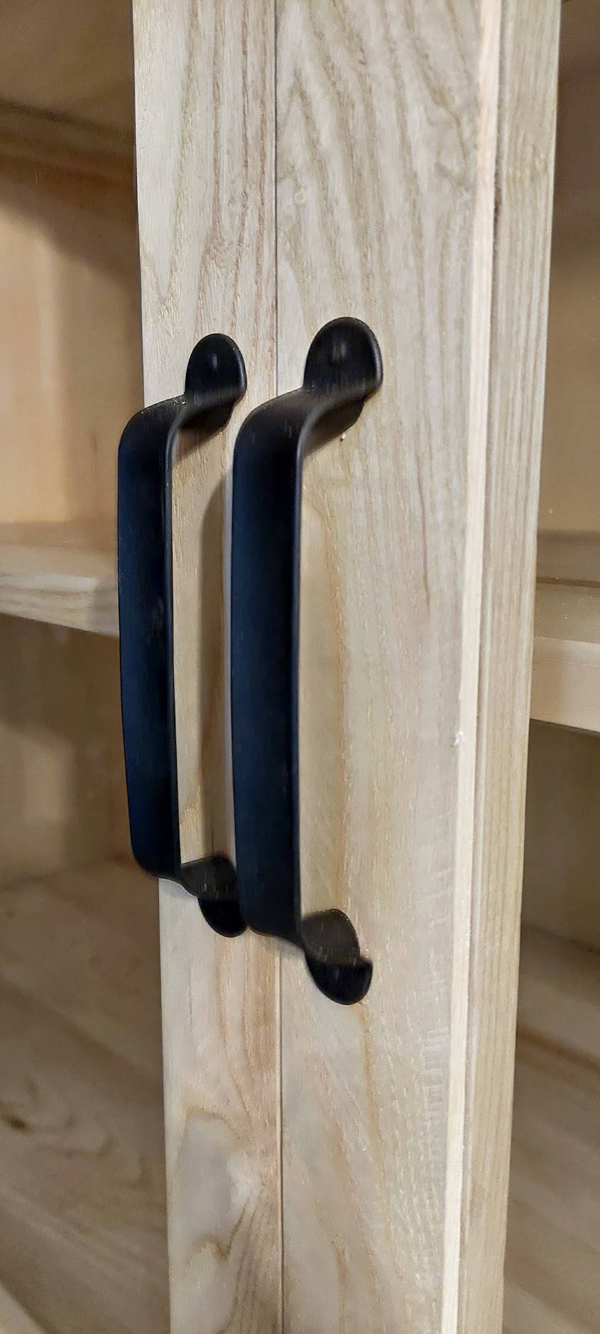 Poignée noire métallique sur buffet en bois massif artisanal.