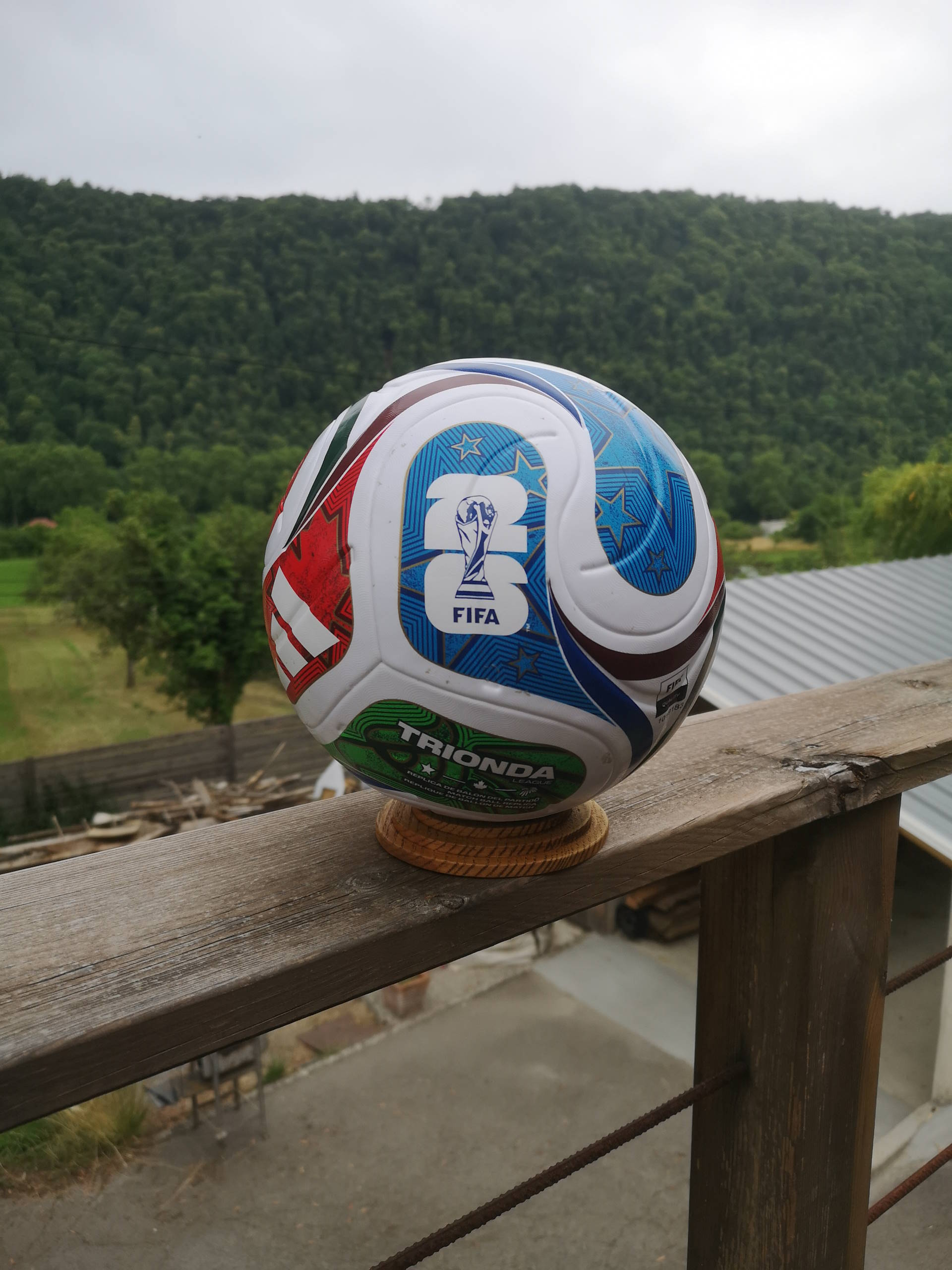 Support ballon foot en bois massif présentant un ballon de football souvenir.